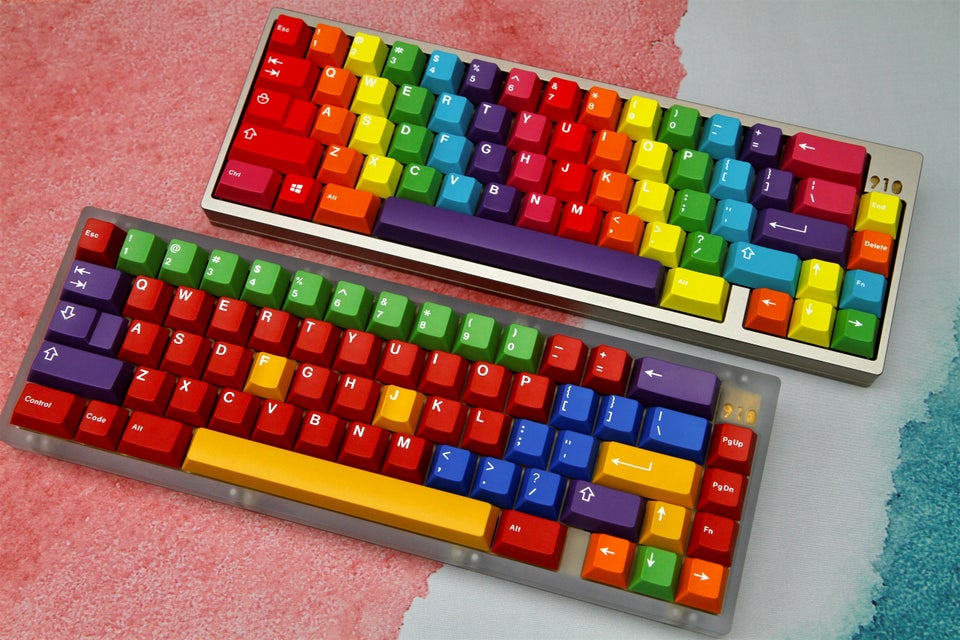 two keyboards with gmk pride a rainbow keycap set